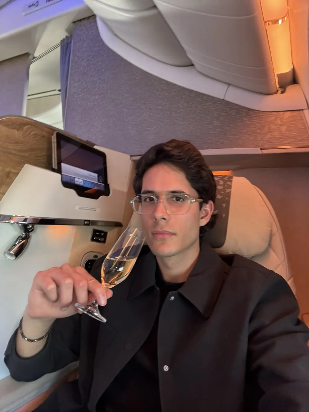 Alex Klaric with champagne in a first class airline suite booked with credit card points
